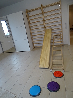 Therapieraum mit Sprossenwand, Balancierbrett und bunten Tastscheiben