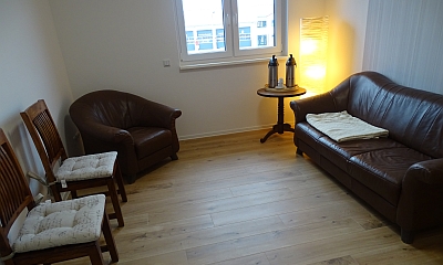 Gemütlicher Raum der Praxis mit Sofa, Sessel und Stehlampe